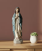 Statue of a religious figure on a table with a candle and decorative items.