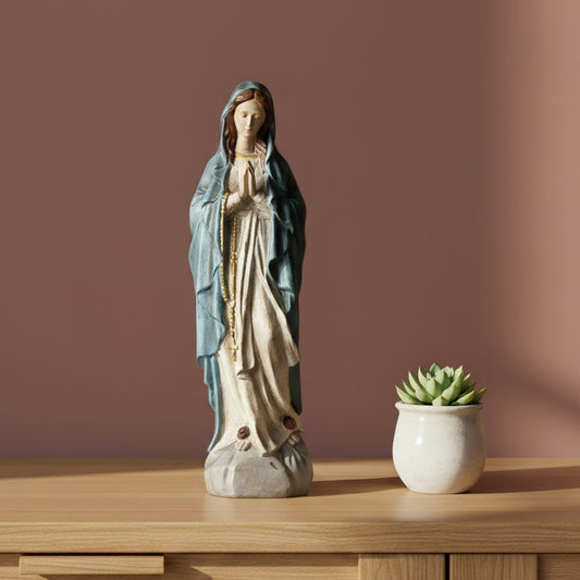 Statue of a religious figure on a table with a candle and decorative items.