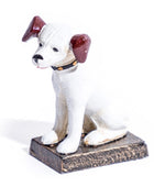 A small white dog figurine with dark reddish-brown ears, a black collar with gold dots, and a distressed brown base, photographed on a white background.