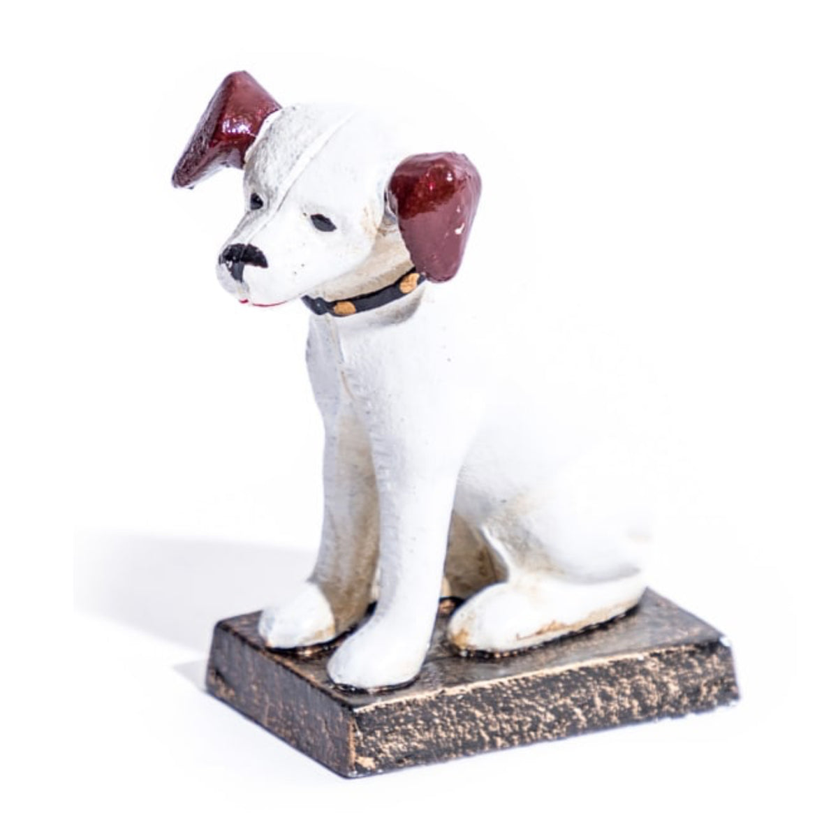 A small white dog figurine with dark reddish-brown ears, a black collar with gold dots, and a distressed brown base, photographed on a white background.