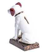 A small white dog figurine with dark reddish-brown ears and eyes, wearing a black and gold collar, sitting on a distressed dark brown rectangular base against a plain white background.