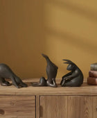 Three black animal sculptures on a wooden surface with a warm brown background