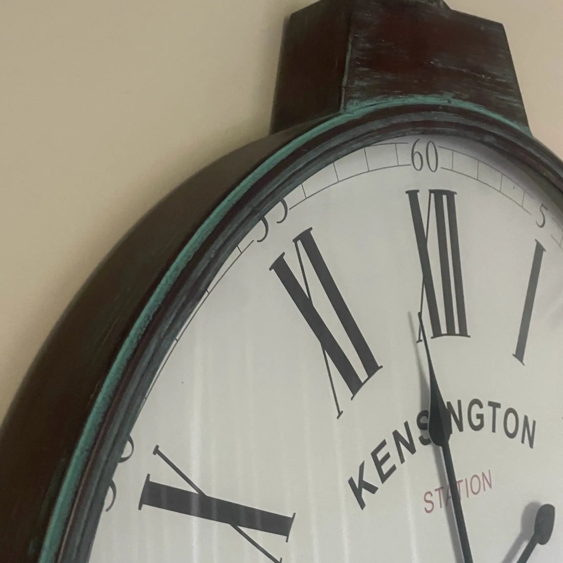 Wall clock with 'Kensington Station' branding on a plain background
