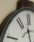 Wall clock with 'Kensington Station' branding on a plain background
