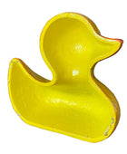 A bright yellow duck-shaped container or tray with a glossy finish, photographed in a warehouse-like setting on a cardboard surface.