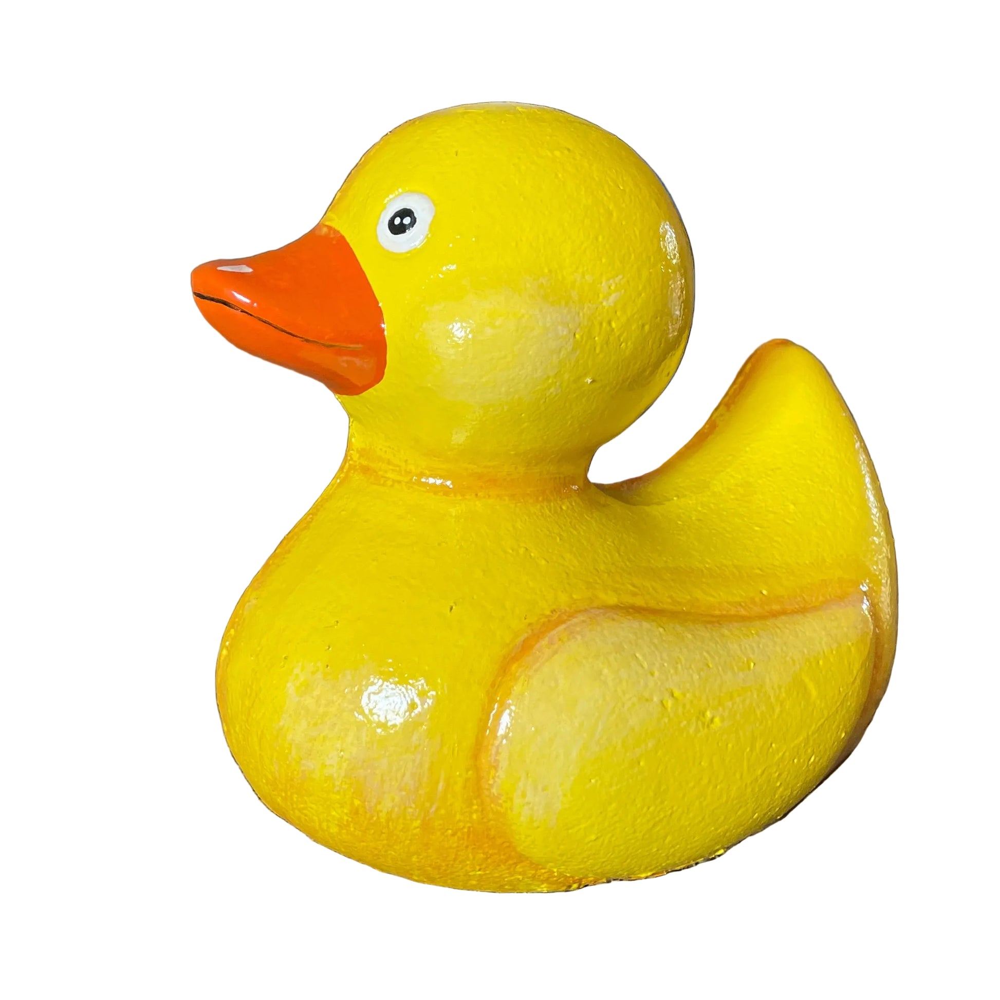 A glossy yellow rubber duck with an orange beak, photographed on a cardboard surface with storage boxes and shelving in the background.
