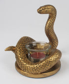 A gold-finished snake-shaped candle holder with a glass candle holder in the center containing a red candle, set against a plain light gray background.