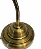 A vintage-style desk lamp with a wide, tiered circular base and a flexible coiled neck, finished in a polished antique brass or bronze metal, shown against a plain white background.