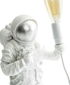 Astronaut figurine holding a light bulb against a white background