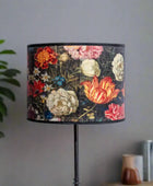 Floral-patterned lampshade on a stand against a neutral wall.