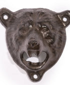 A dark cast iron bear head wall bottle opener with a textured, rustic finish, featuring mounting holes on the ears and bottom, set against a plain white background.