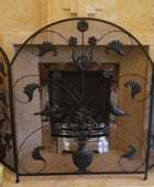 Decorative wrought iron fireplace screen with intricate designs in a room with beige walls.