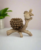 Decorative item with a bird perched on a branch and pine cone on a white background