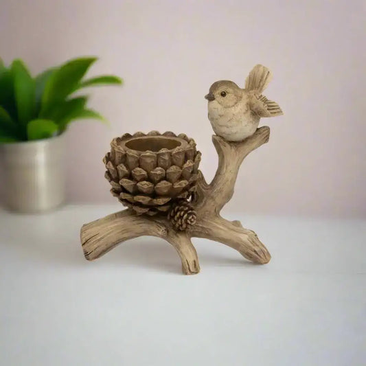 Decorative item with a bird perched on a branch and pine cone on a white background