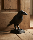Statue of a crow on a wooden floor with a wooden door in the background