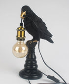 Black bird perched on a lamp with a light bulb, on a white background