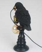 Black bird-shaped lamp with a light bulb on a white background