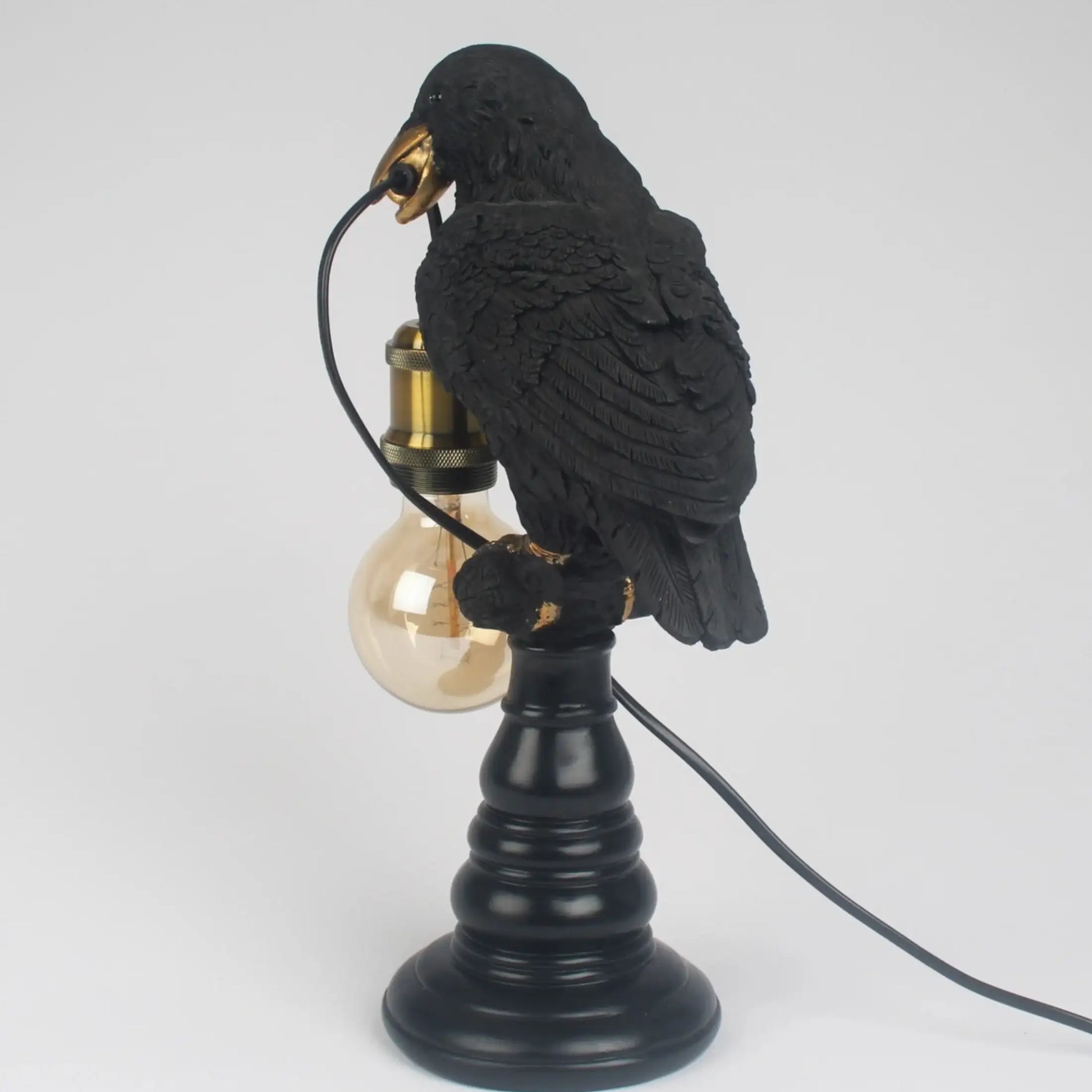 Black bird-shaped lamp with a light bulb on a white background