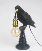 Black bird-shaped lamp with a light bulb on a white background