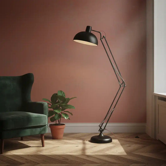 Black floor lamp in a room with a green armchair and plant on a wooden floor.