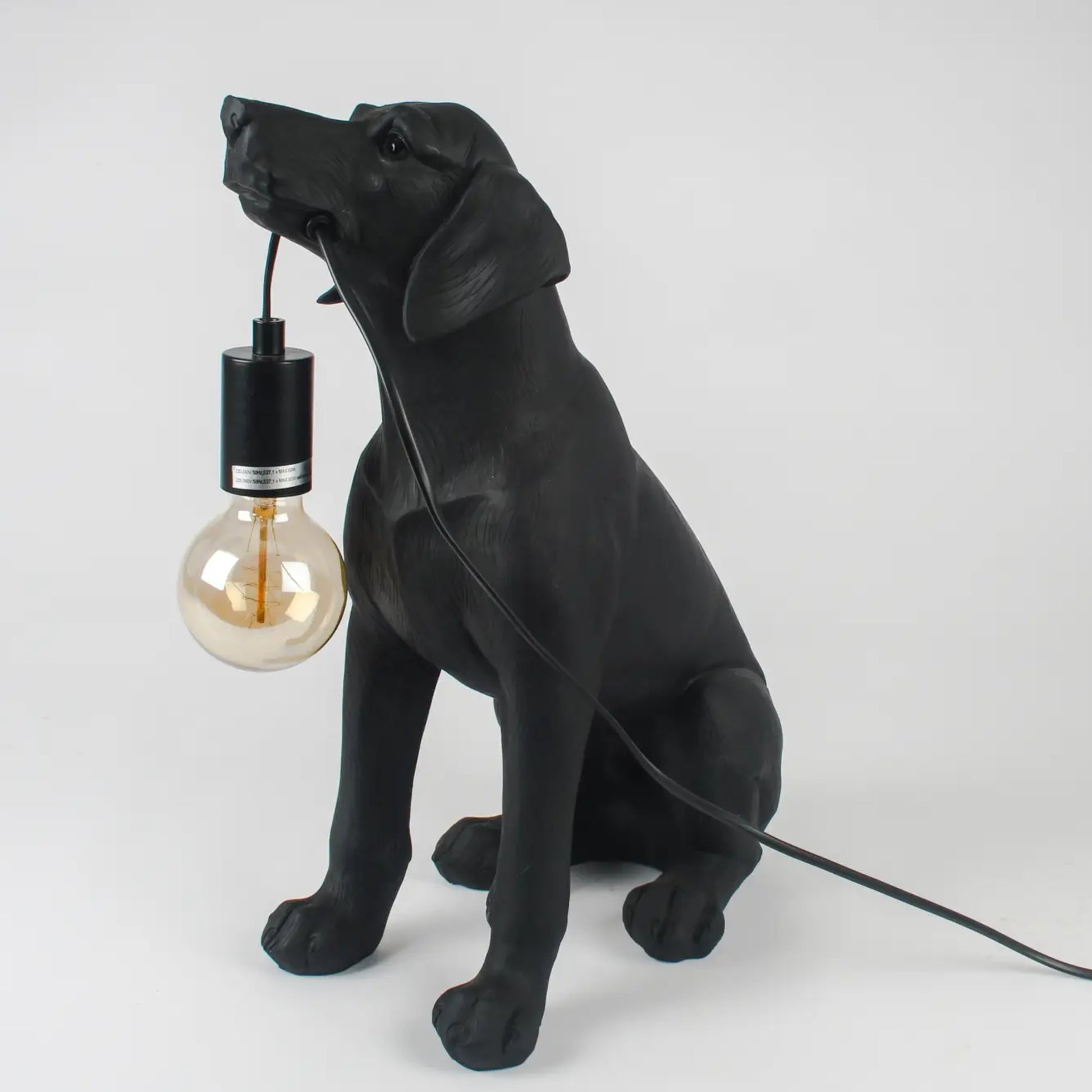 Black dog-shaped lamp with a light bulb on a white background