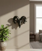 Decorative ram's head wall art above a potted plant in a room with a window.