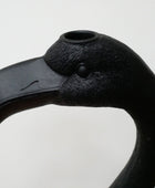 Black flamingo head sculpture on a light gray background