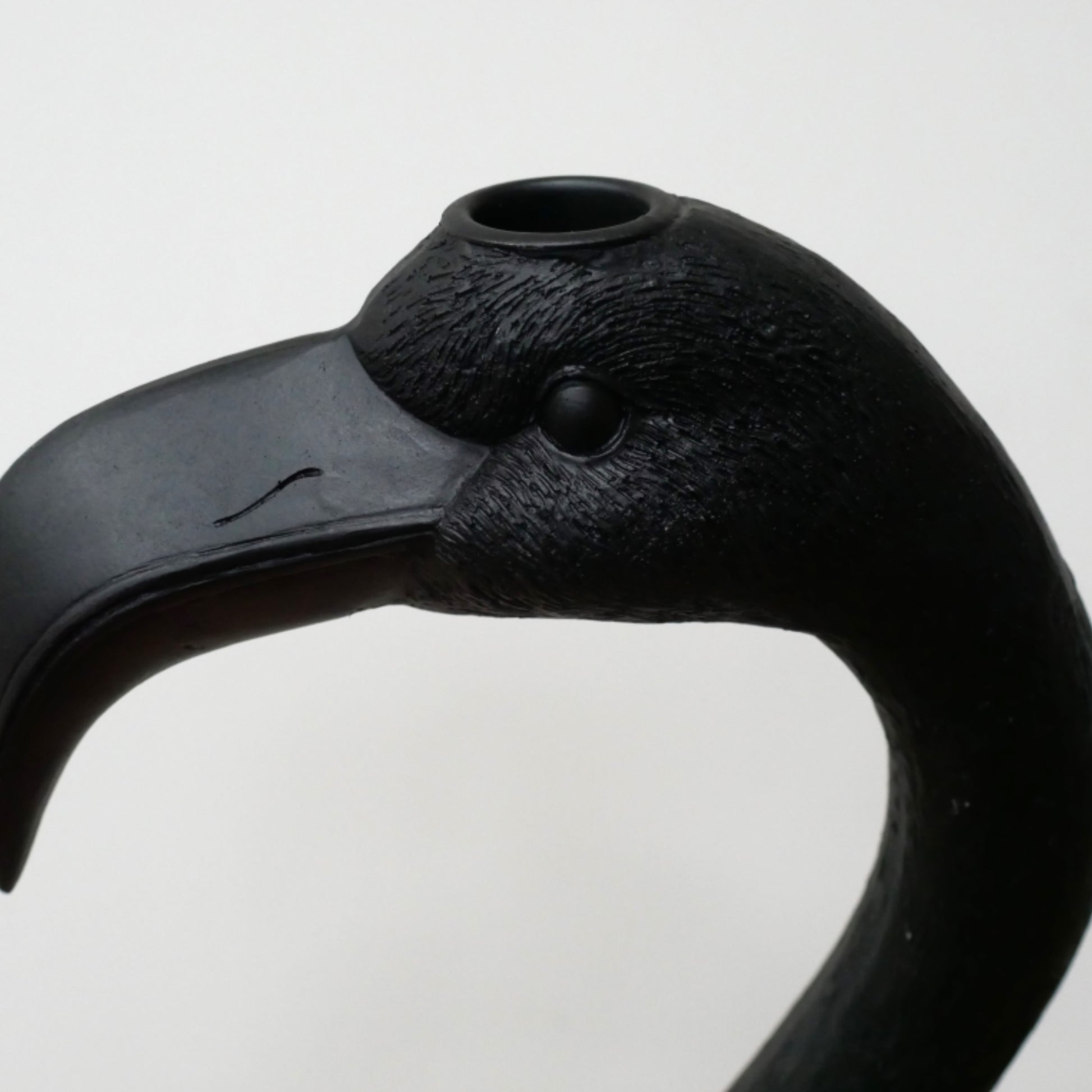 Black flamingo head sculpture on a light gray background