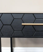 Black geometric-patterned side table with a gold handle on a neutral background