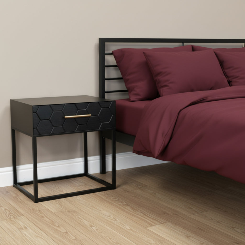 Black geometric-patterned side table with a gold handle on a gray surface.