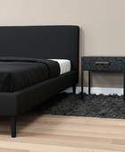 Modern bedroom with a black upholstered bed and hexagonal patterned nightstand.