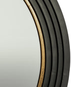 Close-up of a round wall mirror with a dark charcoal gray frame featuring a warm gold-toned inner trim.