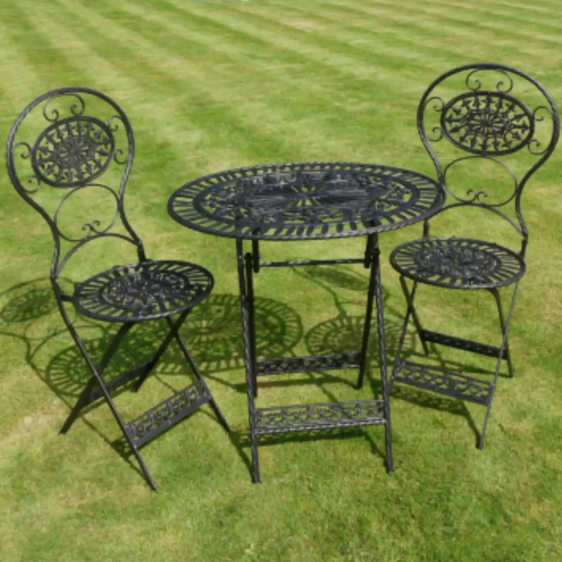Black metal garden table and chairs set on a grassy background
