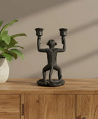 Decorative monkey candle holder on a wooden surface with a plant in the background