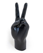 A glossy black hand sculpture or decorative object shaped like a human hand making a peace sign, photographed against a plain white background.