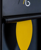 Close-up of a black surface with a yellow leaf-shaped object and a logo in the corner.