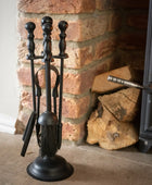 Black fireplace tool set in front of a brick fireplace with logs.