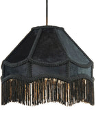 A black fabric pendant lampshade with intricate braided trim and a long fringe hanging from the bottom, suspended by a thin black cord against a plain white background.