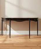Dark wooden table against a beige wall with a potted plant on a wooden floor.