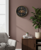 Wall clock on a brown wall with a gray armchair and wooden cabinet in the foreground