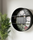 Round black wall shelf with floral design on a white wall