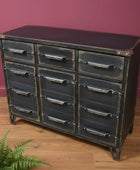 Industrial-style metal dresser with multiple drawers against a brick wall.