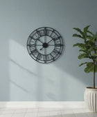 Decorative wall clock on a light blue wall with a potted plant below.