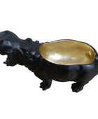 Black hippo figurine with a gold belly on a wooden surface