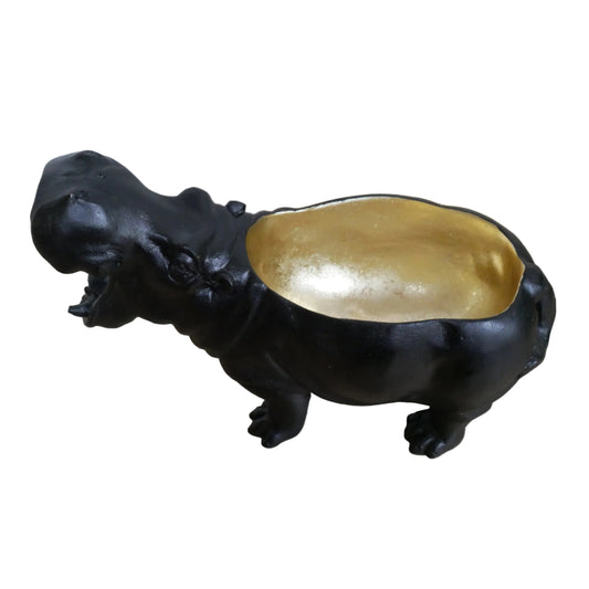 Black hippo figurine with a gold belly on a wooden surface