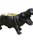 Black hippo-shaped candle holder on a wooden surface with a white background