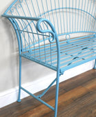 Blue metal bench against a white wall on a wooden floor