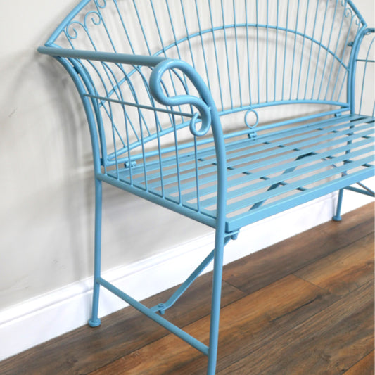 Blue metal bench against a white wall on a wooden floor