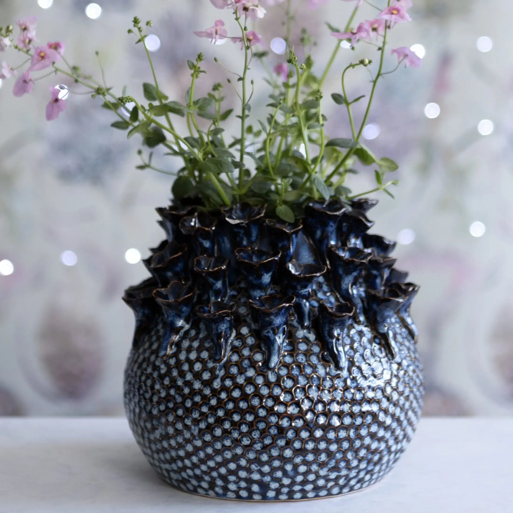Decorative vase with textured surface and floral arrangement on a blurred background