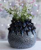 Decorative vase with textured surface and floral arrangement on a blurred background